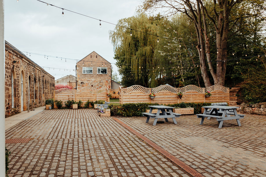 Courtyard area of The Venue, Eskmills, decorated with picnic tables and hanging baskets